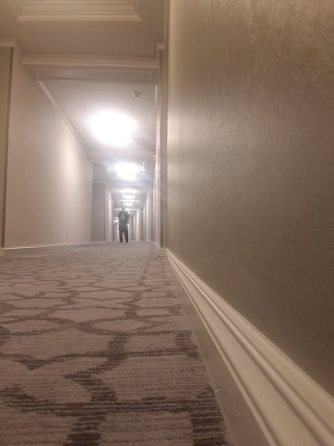 A hotel hallway with warm light glowing at the far end